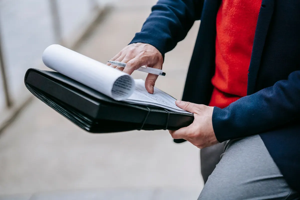A person leafing through papers held in a folder